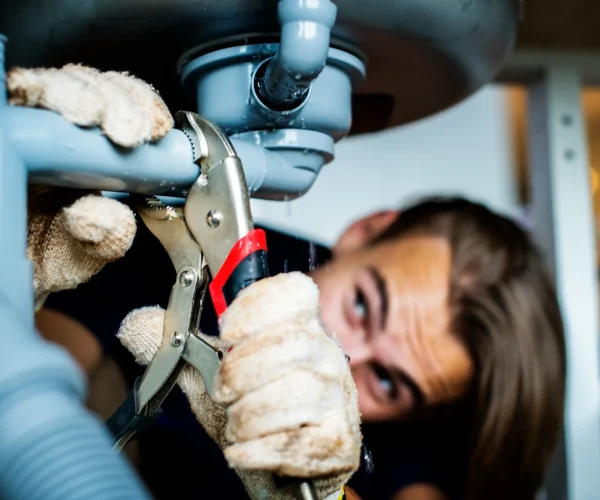 Plombier urgence utilisant une pince pour réparer une fuite sous un évier